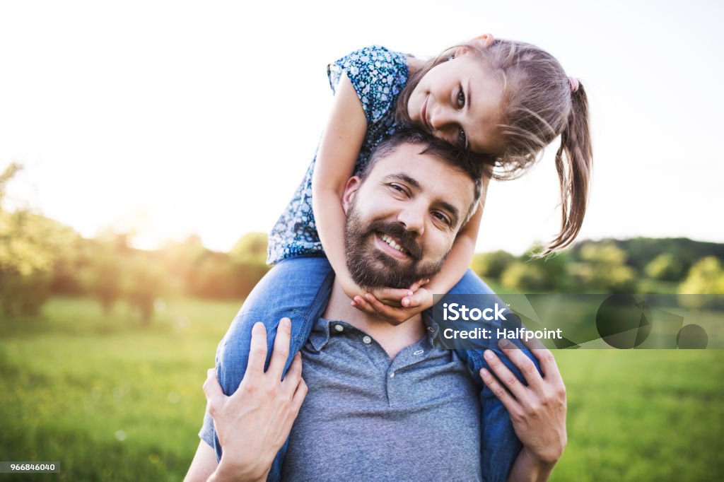 Father giving small daughter a piggyback ride in spring nature. Mature father giving a small daughter a piggyback ride in spring nature. Single Father Stock Photo