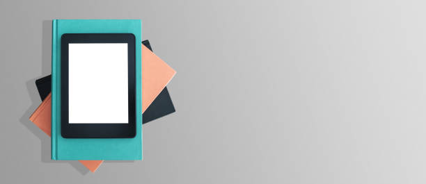 top view of e-book reader on stack of books on gray desktop