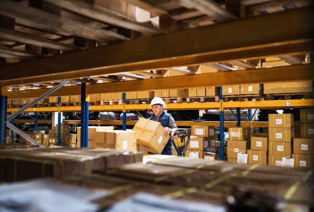 istock Senior male warehouse worker or a supervisor unloading a pallet truck with boxes. 966855958