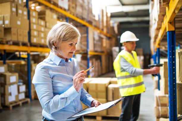 istock Senior woman manager and man worker working in a warehouse. 966856170