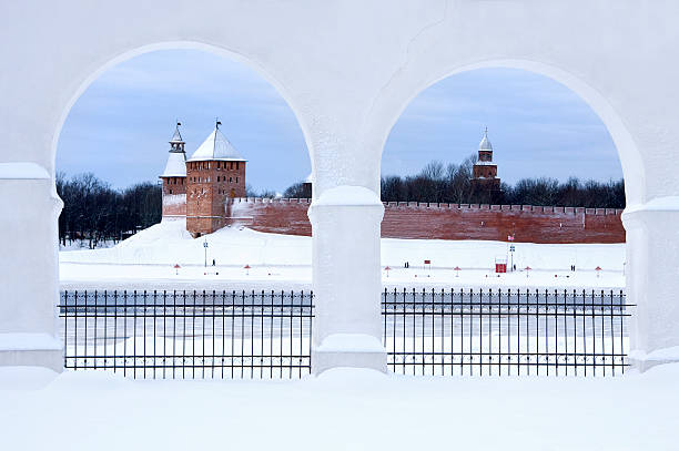 zwei schneeweiße bögen schaffen wunderschönen rahmen für alte rote burg - novgorod stock-fotos und bilder