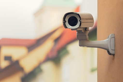 A security camera on an apartment building wall in a city environment.