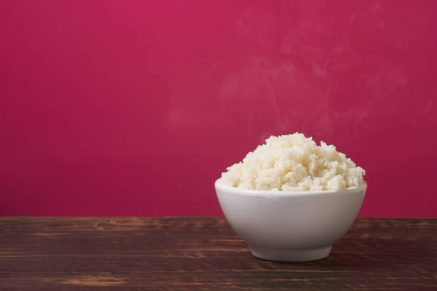 istock Plain rice in a white bowl with smoke on the table and pink background 966860198