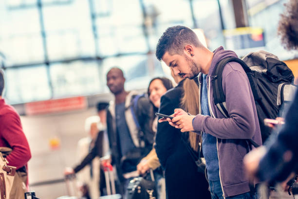 istock Man standing in line at an airport using a smart phone 966860932