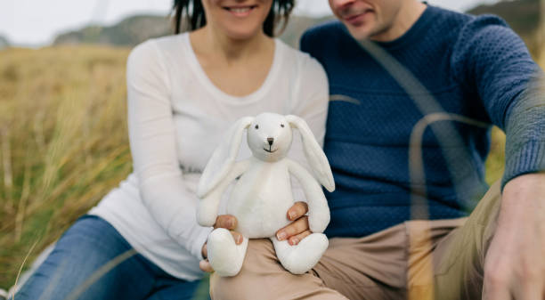 Couple showing a stuffed bunny Happy couple showing a stuffed bunny announcing their pregnancy funny pregnancy announcements stock pictures, royalty-free photos & images