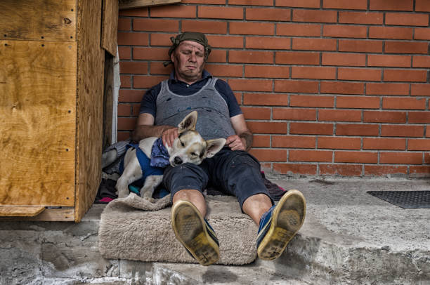 Cтоковое фото Мужчина и собака спят, сидя на бетоне у кирпичной стены