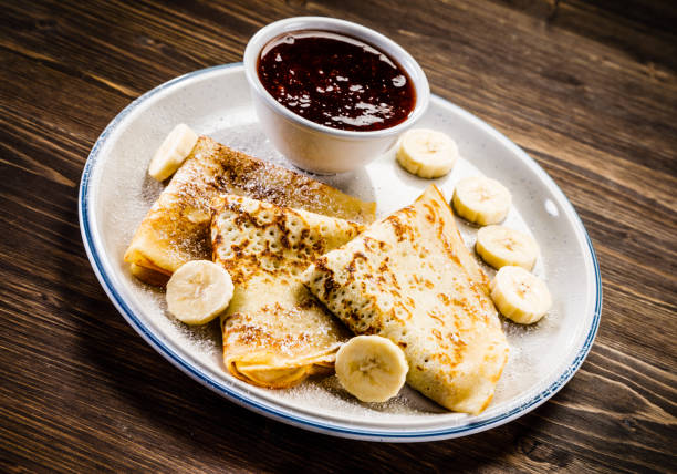 istock Crepes with banana, cream and fruit syrup 966864696