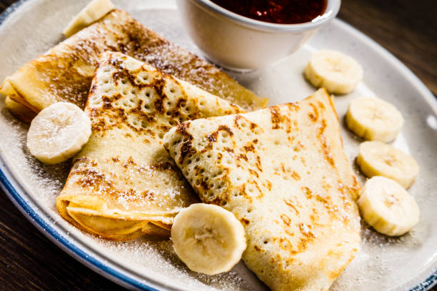 Crepes with banana, cream and fruit syrup Pancakes with fruit appetizer plate stock pictures, royalty-free photos & images