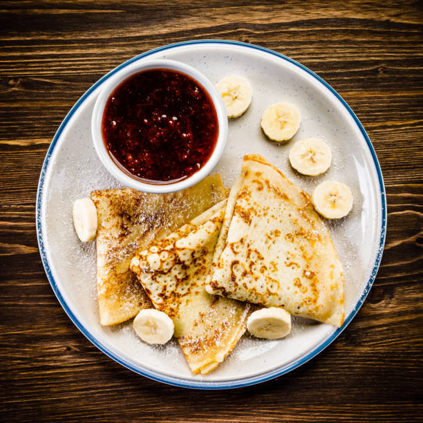 istock Crepes with banana, cream and fruit syrup 966864916