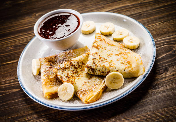 istock Crepes with banana, cream and fruit syrup 966865038