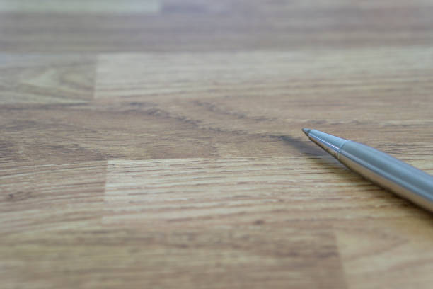 istock Metal ballpoint pen lay in wooden table 966869376
