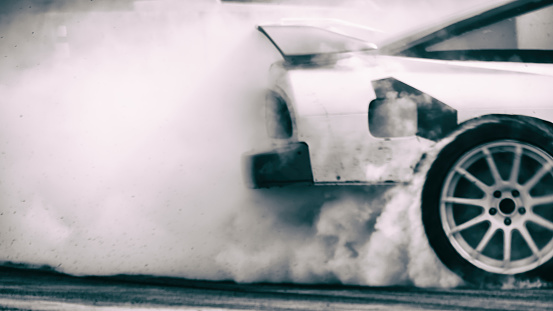 Blurred vintage image of car drifting with a lot of smoke on race track. Motor sport concept.