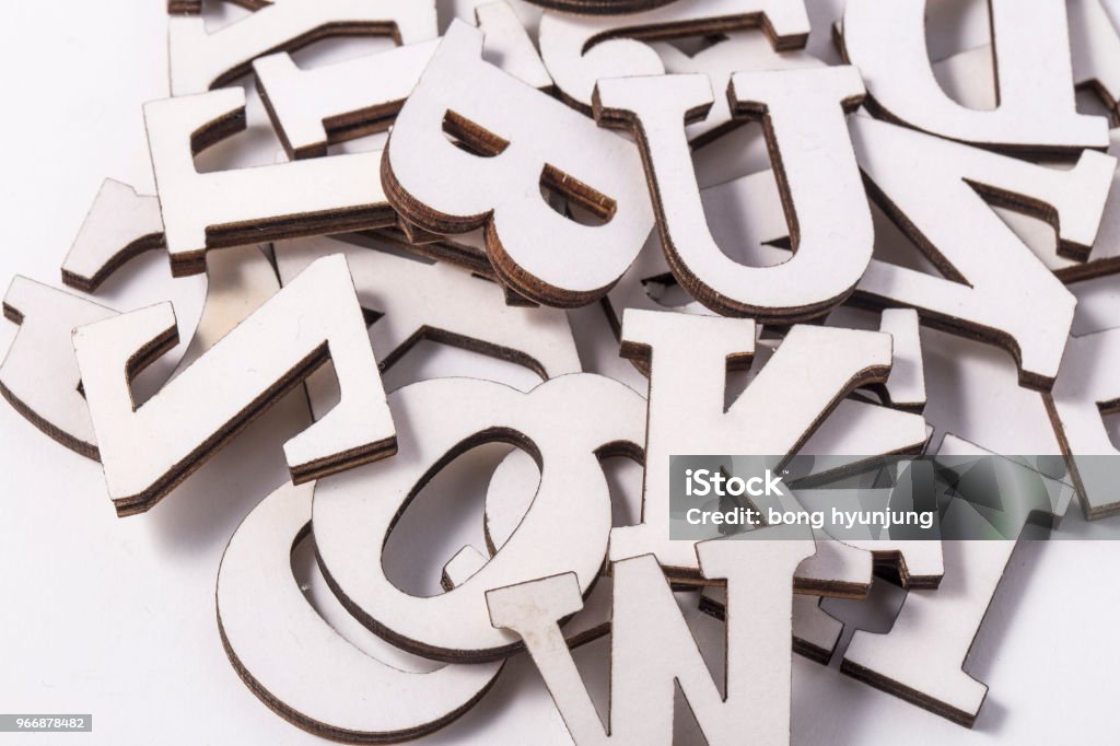 Alphabet letters on wooden scrabble pieces, isolated on white. Tile Stock Photo