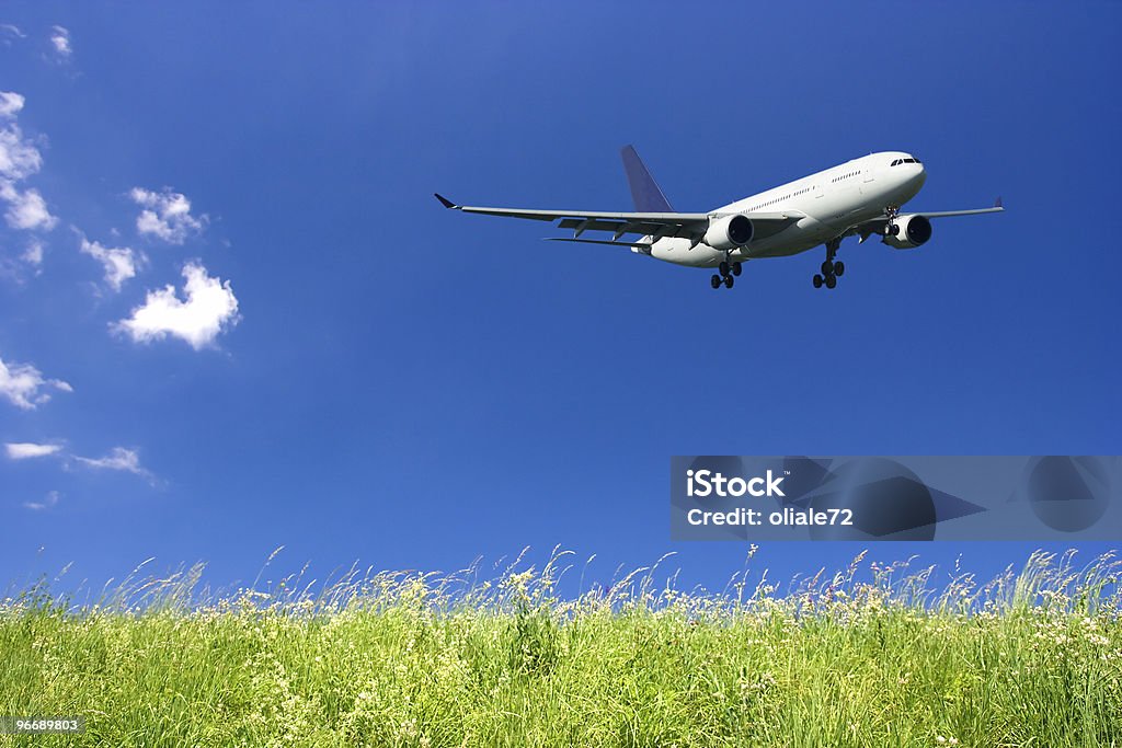 Avión volando en el cielo azul y verde césped - Foto de stock de Aeropuerto libre de derechos