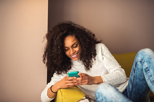 Happy attractive african american girl texting on a mobile phone.