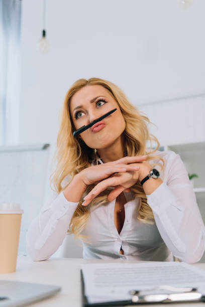 istock businesswoman grimacing and making mustache with pen 966905490