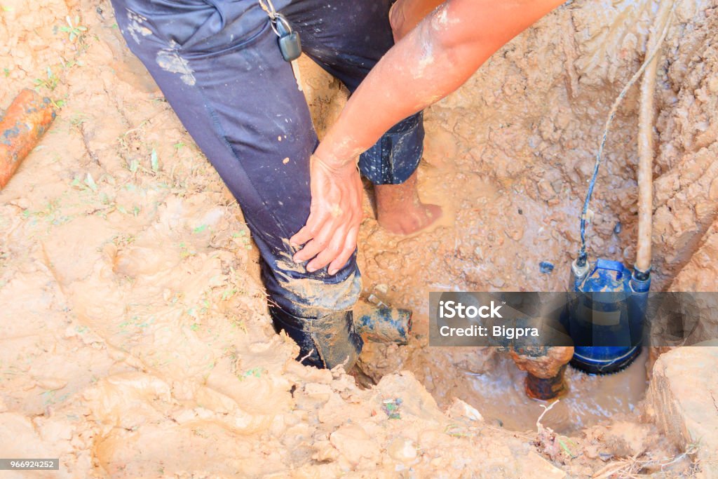 male plumber are repair broken pipe in hole with plumbing water flow outdoor and sunlight with copy space add text Adult Stock Photo