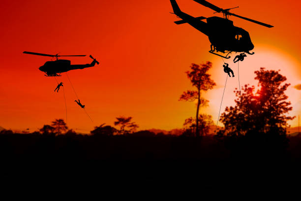 istock Silhouette Soldiers rappel down to attack from helicopter with sunset and copy space add text ( Concept stop hostilities To peace) 966937298