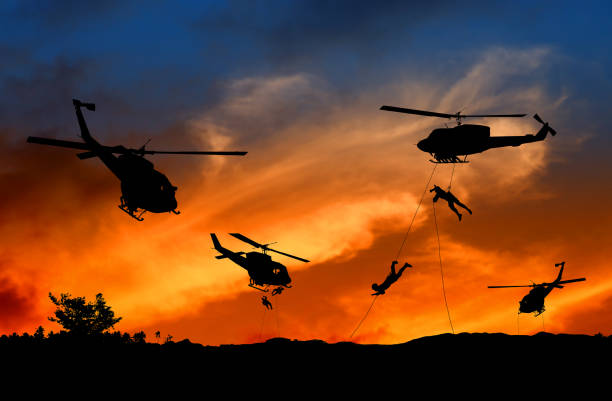istock Silhouette Soldiers rappel down to attack from helicopter with sunset and copy space add text ( Concept stop hostilities To peace) 966937388