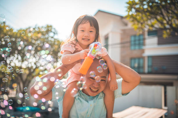 istock Father and daughter blowing bubbles in backyard 966947070