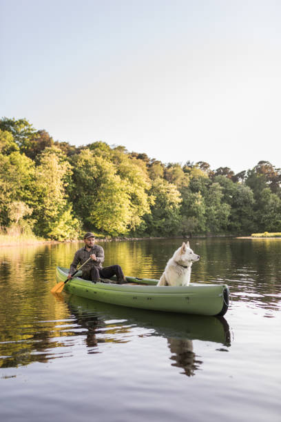 istock Man and dog canoeing on river 966948700