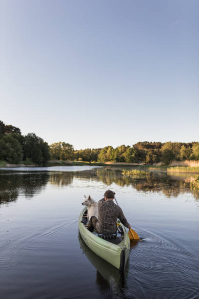 istock Man and dog canoeing on river 966951006