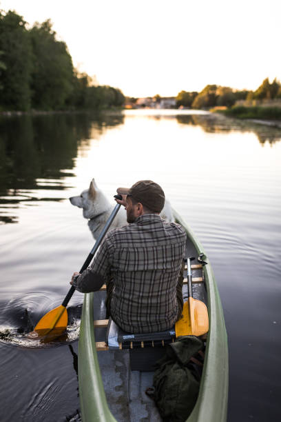 istock Man and pet dog canoeing on river 966951546