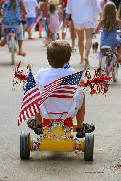 Young boy shows patriotism in 4th of July Parade red white blue bike stock pictures, royalty-free photos & images