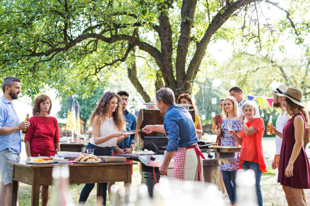celebración familiar o una fiesta de barbacoa fuera en el patio trasero. - barbacoa reunión fotografías e imágenes de stock