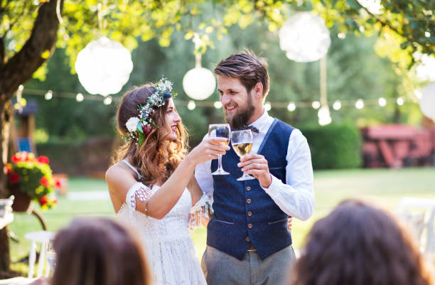 istock Bride and groom with guests at wedding reception outside in the backyard. 966953430