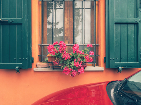 a red car is parked in front of a beautiful cottage house
