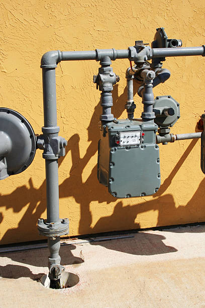 Gray Gas Utility Meter against Yellow Stucco Wall stock photo