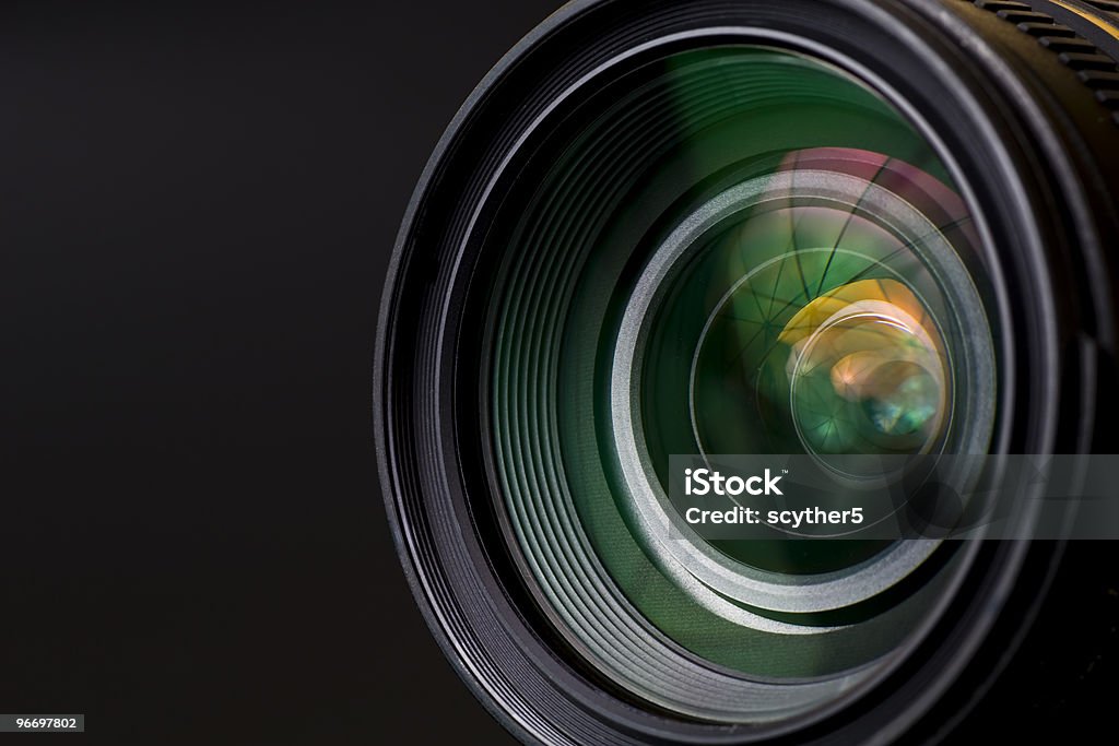 Close-up image of black camera lens objective with lense reflections. Shot in studio. Movie Camera Stock Photo
