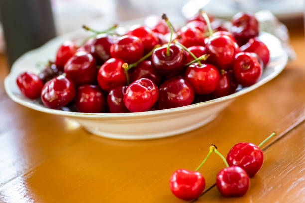 plate full of cherries on a wooden table
