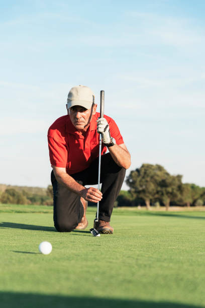 istock Senior golf player concentrating for putting on green. 966992732