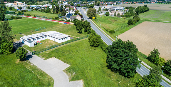 Aerial view of the clubhouse of a regional football club on the outskirts of the city next to a big street, football field in the background, near Wolfsburg