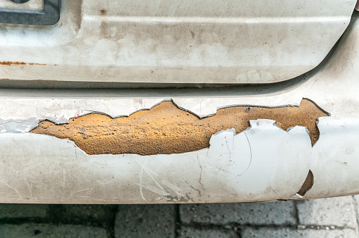 Broken and damaged rear bumper on the dirty white car close up