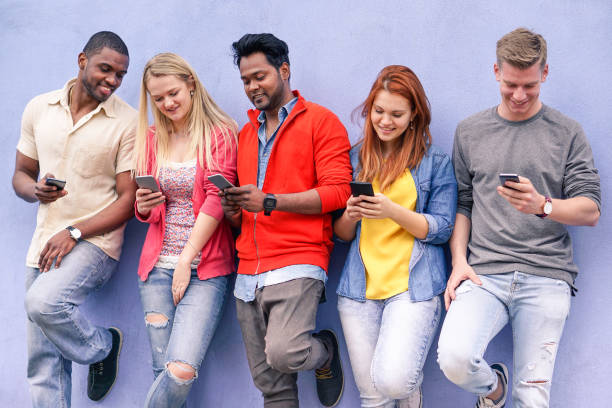 istock Cheerful young friends looking smart phone - Mixed race people using mobile phone with blue wall background - Friendship fun concept with trend technology interaction - Soft focus on guys in middle 967034514