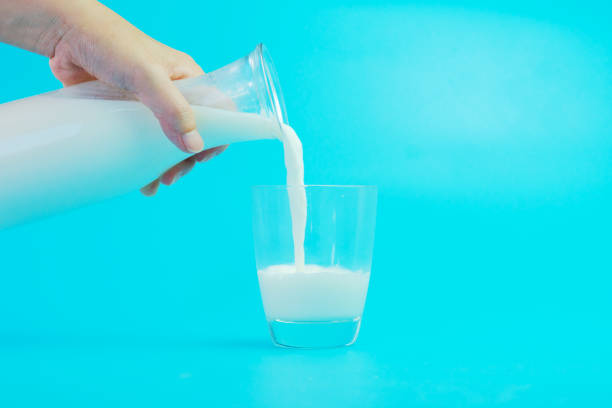 istock Milk poured into a glass on blue background 967035998