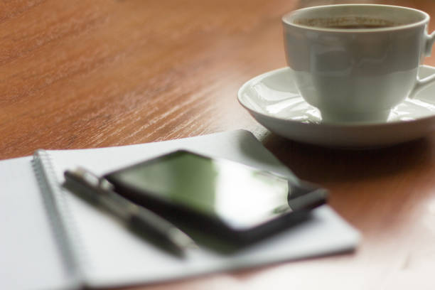 istock morning hot coffee, notebook and phone on the table 967036076