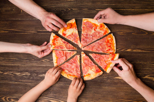 istock Hands taking pizza slices from wooden table, close up view 967037846