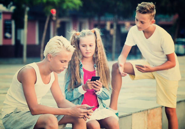 istock Modern children relaxing together in town square using mobile gadgets 967039466