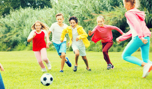 istock Kids playing football in park 967069276