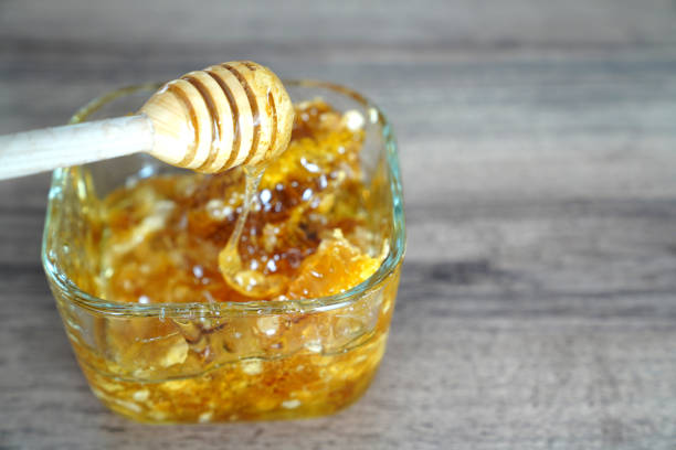 istock Wooden dipper with quadrangular glass bowl of honey on dark walnut table 967069762