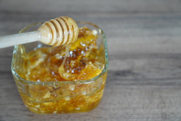istock Wooden dipper with quadrangular glass bowl of honey on dark walnut table 967069792