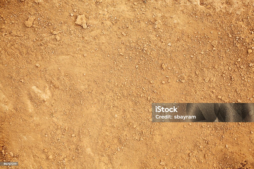 Background of earth and dirt Photograph of tan colored dirt. Small clumps of dirt are sprinkled randomly over a layer of dry dirt and sand. Dirt Stock Photo