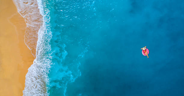 Swimming in clear turquoise sea at summer Aerial view of swimming in clear turquoise water. Woman on a swimming float. Mediterranean sea. pool raft stock pictures, royalty-free photos & images