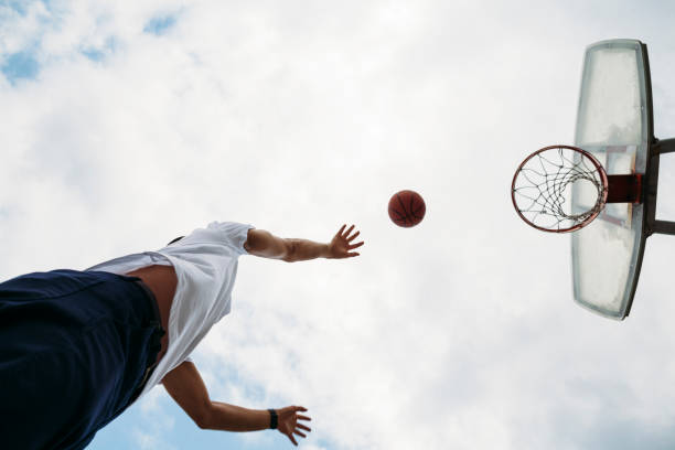 Man playing basketball in public basketball court A Japanese young man is playing basketball in a public basketball court in Tokyo. low angle street japan stock pictures, royalty-free photos & images