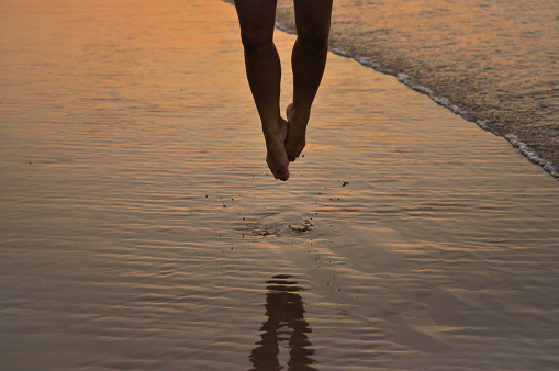 Lower body of a woman jumping on the sand