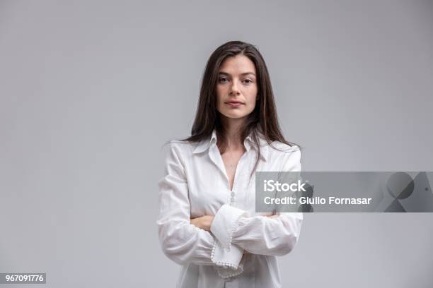 Mujer De Pelo Largo De Pie Con Los Brazos Cruzados Foto de stock y más banco de imágenes de Mujeres - Mujeres, Una sola mujer, Serio